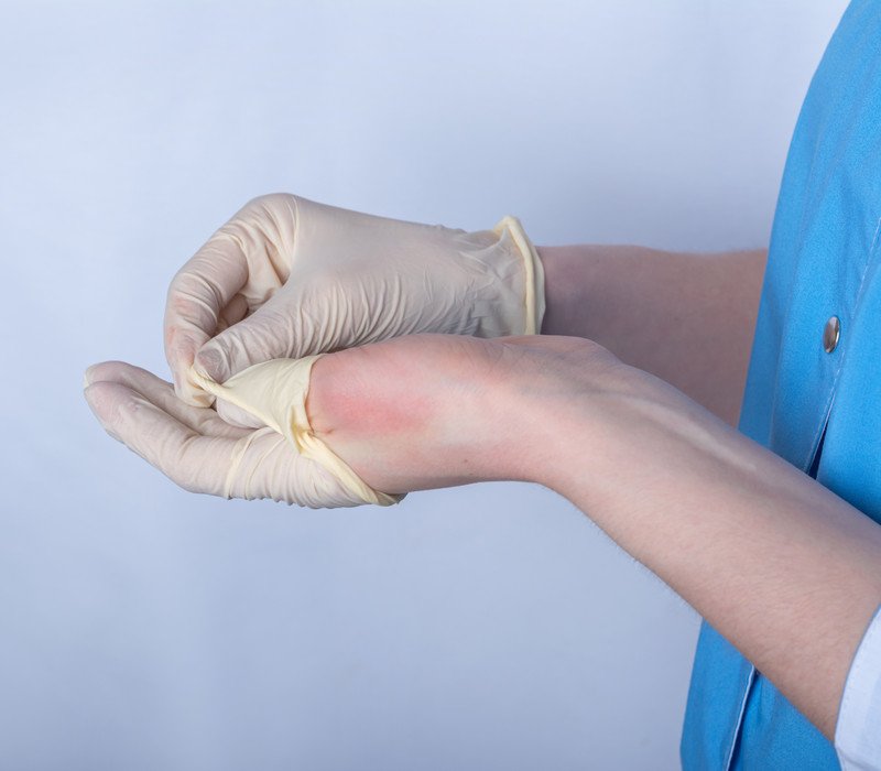 a nurse in uniform removes rubber medical disposable gloves from